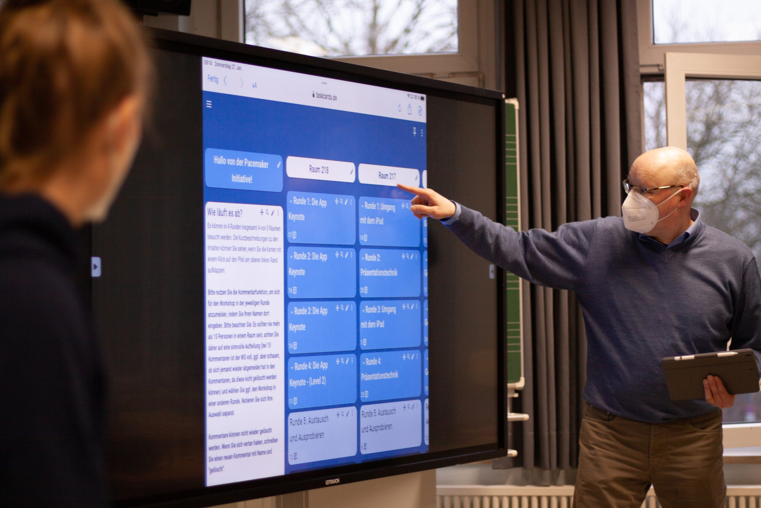 Ein Mann zeigt auf einer digitalen Tafel auf ein TaskCards.